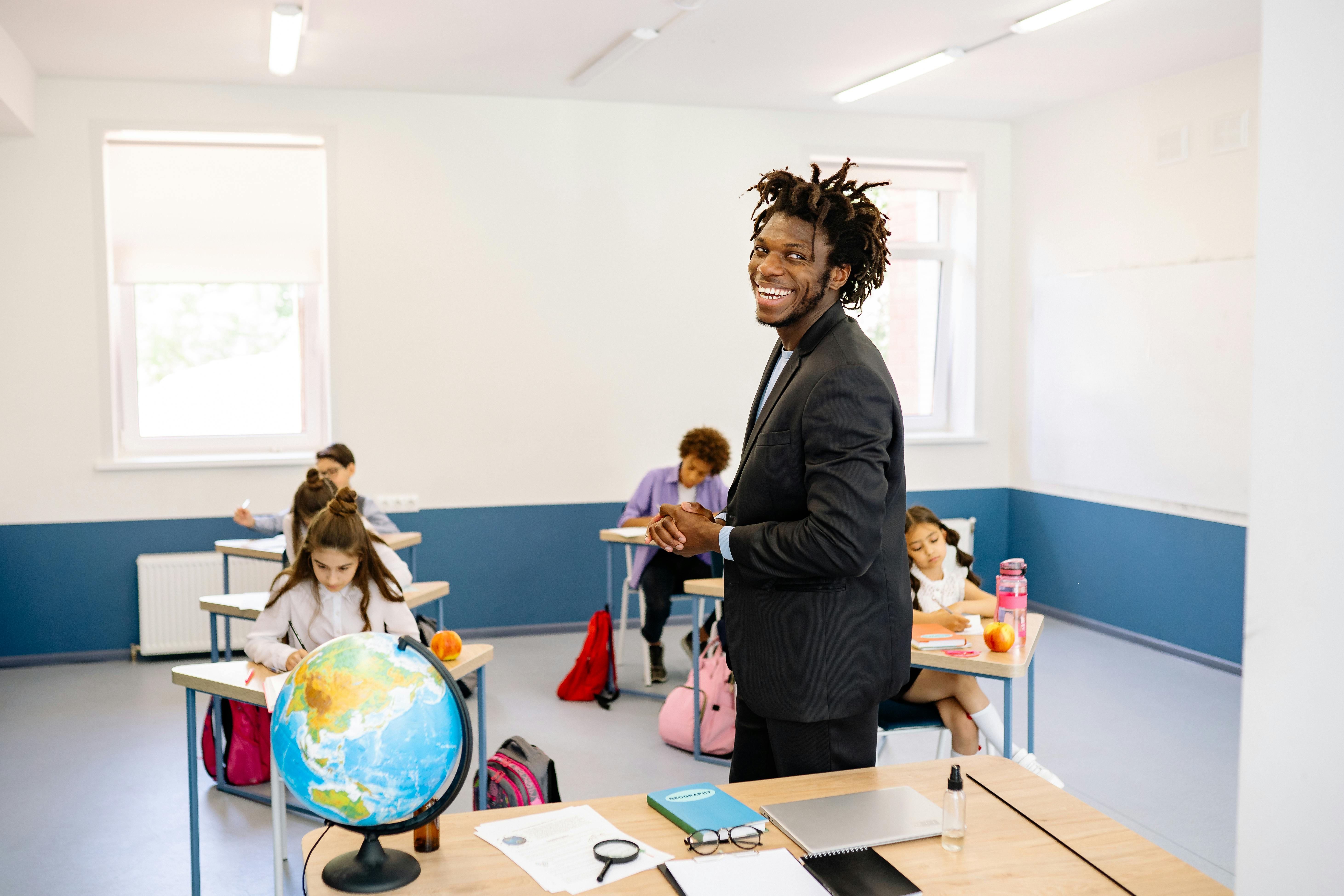 Teacher smiling in classroom while pupils work at desks during HAF programme activities in school